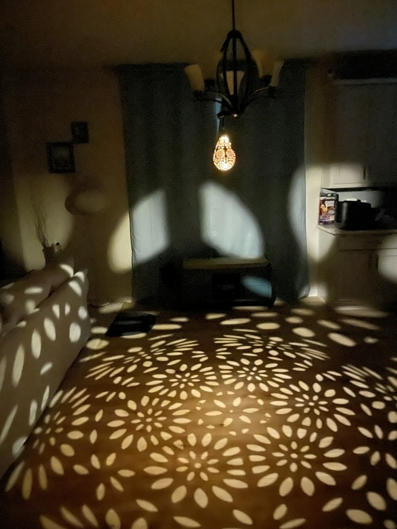 Warm patterned light from a pendant lamp across a living room floor and sofa