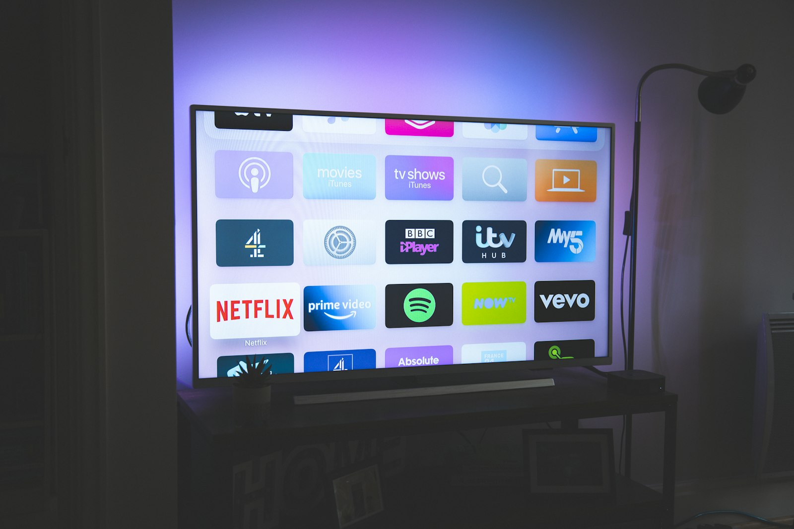 Living room TV on a media console with soft bias lighting on the wall